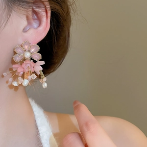 Detailed view of pink petal earrings with freshwater pearl tassels on a model