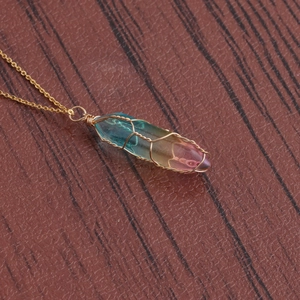 Detail of gradient crystal hexagonal column pendant with gold wire wrap on wood