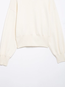 Detailed macro view of the ribbed hem and cuffs on this cream knit cardigan sweater