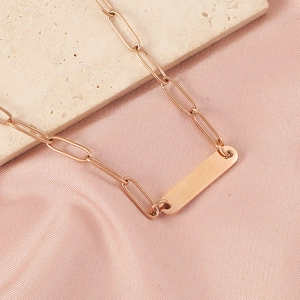 Detailed view of rose gold rectangle bar necklace on elegant silk background