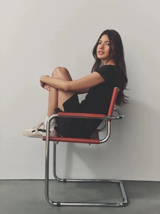 Slim fit black mini dress with V-neckline paired with casual sneakers in a studio setting