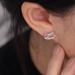 Close-up of a silver rocking horse stud earring with sparkling cubic zirconia on earlobe