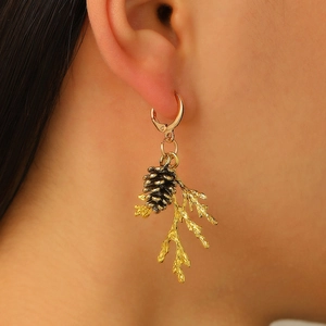 Detailed close-up of a vintage golden pine cone and branch earring worn on a model's ear