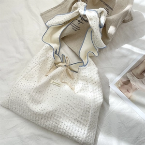 Close-up of texture pleated polka dot canvas bag with blue ruffle tie strap detail