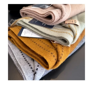 Detail of folded 100% wool scarves in pink, green, yellow, and grey with texture