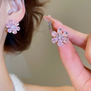 Close-up of flower stud earrings featuring purple zircon petals and center diamond accent