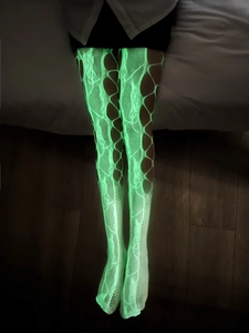 Détail de bas résille vert fluo avec déchirures punk et effet luminescent