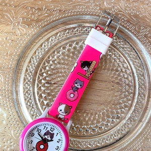 Detail view of pink silicone watch strap with cute cartoon cat pattern on a glass plate