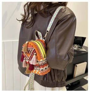 Detail of woven canvas backpack featuring colorful ethnic jacquard and tassel charms