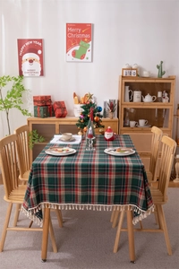 Close-up of festive red and green plaid tablecloth with cream tassels in Christmas setting