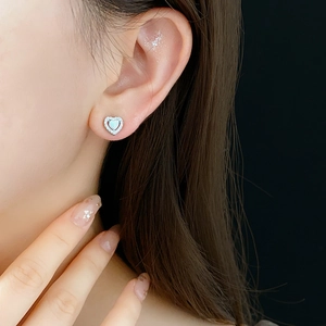 Close-up of heart-shaped earring featuring a white opal center and sparkling zircon halo