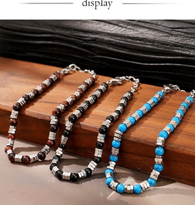 Detail of beaded men's bracelets with tiger eye, onyx and turquoise stones on wood base