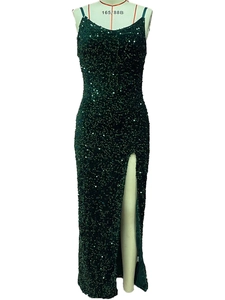 Détail d'une robe longue à paillettes vert foncé montrant la fente et le tissu brillant