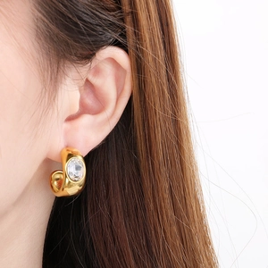Close-up of a vintage gold C-shaped stainless steel earring with diamond on a model