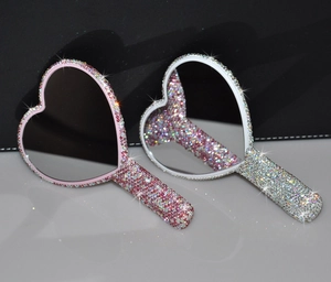 Nahaufnahme herzförmiger Handspiegel mit funkelnden rosa und silbernen Strasssteinen