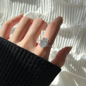 Macro shot of an oval-cut diamond ring on a hand with sparkling pave-set stones
