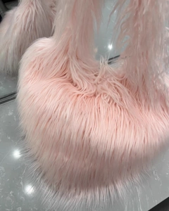 Macro view of fluffy pink faux fur texture and soft plush material on heart-shaped bag