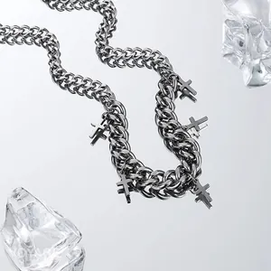 Close-up of stainless steel curb chain necklace with multiple cross pendants on ice