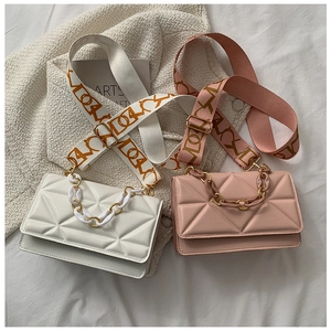 Detail view of pink and white quilted crossbody bags with chain and wide straps