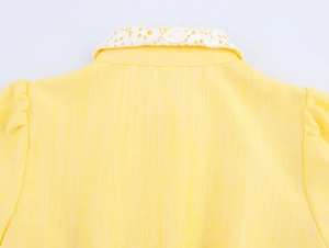 Close-up of yellow dress back featuring delicate white lace collar and textured fabric
