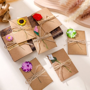 Close-up of mini kraft paper envelopes with assorted artificial flowers and twine