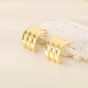 Macro view of gold 18k stainless steel C-shape triple hoop earrings on white mineral stone