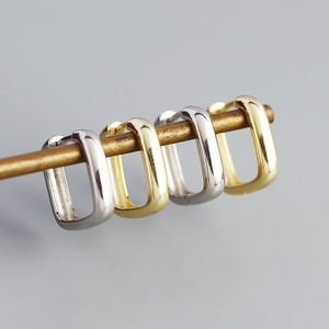 Minimalist square hoop earrings in gold and silver finish hanging on a metal rod display
