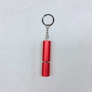 Detail of red cylindrical travel perfume atomizer with portable silver keychain and chain