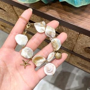 Detailed macro view of baroque pearl bracelet with gold starfish and seashell charms