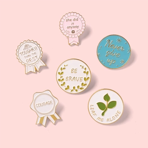 Detailed view of six colorful enamel pins with motivational quotes and gold edges