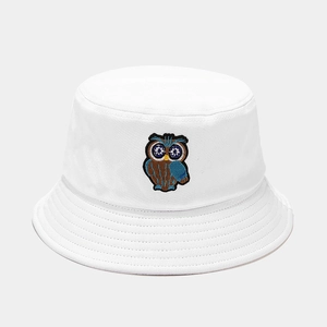 Detailed view of owl embroidery on a white cotton bucket hat with parallel stitching