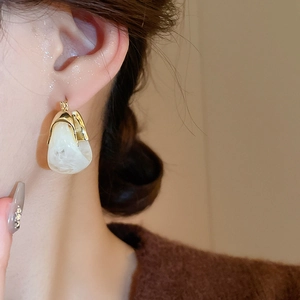 Close-up of vintage U-shaped resin earrings with marble texture on model