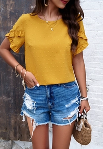 Detail of a yellow polka dot blouse with ruffle sleeves and distressed blue denim shorts