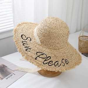 Detail of raffia sun hat with 'Sun Please' embroidery and delicate lace ribbon tie