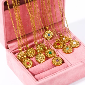 Close-up of gold coin pendants with colored birthstones in a pink velvet jewelry box