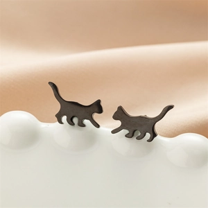 Macro shot of cute matte black stainless steel cat-shaped stud earrings on a ceramic display