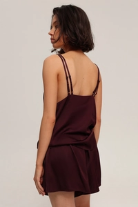 Detail of burgundy satin sleepwear set showing silk texture and lace stitching on the side