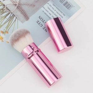 Close-up of portable retractable makeup brush with pink metallic finish and dual-tone bristles