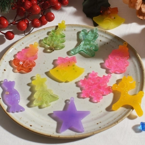 Colorful resin Christmas pendants including gingerbread man and tree on a white ceramic plate