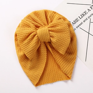 Detailed view of yellow waffle knit baby turban hat with a large bow decoration