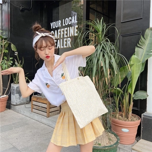 Outdoor street shot of a model carrying the daisy print canvas tote bag in beige