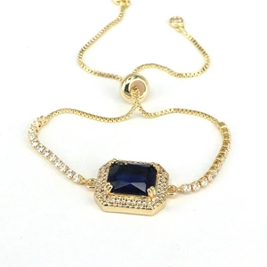 Detail of adjustable gold tennis bracelet with halo-set navy blue square zircon stone