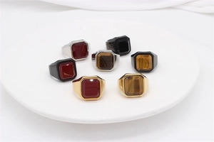 Collection of square gemstone signet rings with tiger eye and agate on a ceramic tray