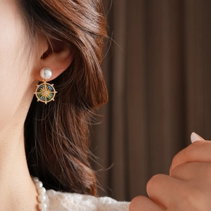 Detail of gold-plated earring with green mother-of-pearl and star motif on model