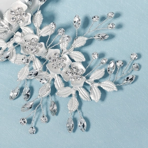 Détail d'une pince à cheveux de mariée avec fleurs argentées, feuilles et cristaux