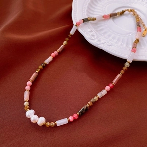 Close-up of handmade floral ceramic beaded necklace with pearls and gold lobster clasp