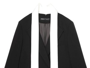 Détail d'un blazer noir avec col écharpe blanc contrastant et étiquette de taille L