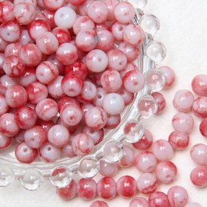 Close-up of red and white 8mm crackle glass beads for DIY jewelry making in glass bowl