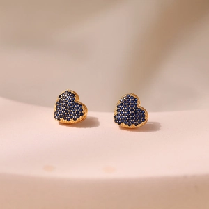 Detailed close-up of heart stud earrings with blue cubic zirconia in 18K gold plating