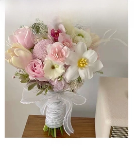 Detail of floral bouquet wrapped with pearl-studded mesh ribbon and delicate pink roses